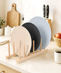 Eight Pack Bamboo Wooden Plate Rack Six Slots Kitchen Dish Drying Organizer For Pots Lids Cutting Boards Cups in use with plates arranged.
