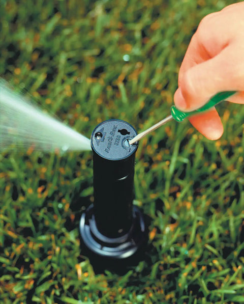 Adjusting Simple Adjust Gear Drive Rotor 32SA in lawn with screwdriver, showing spray pattern and water-lubricated gear-driven design