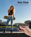Person holding remote for 66 Inch Phone Tripod With Remote And Clamp Mount For iPhone And Android Extendable Stand, skateboarder in background.