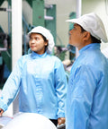 Kickass Anti Static ESD Lab Coat Engineered For The Daily Grind Featuring Conductive Polyester Weave That Slaps Electrostatic Buildup Cold With Reliable Cuff Lapel Collar Seal Flat Out Legit Industrial Wear For Lab And Plant Crews Unisex Blue worn by two workers in a clean industrial setting.