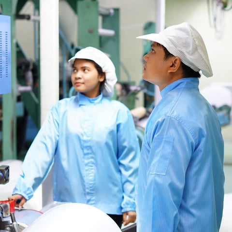 Kickass Anti Static ESD Lab Coat Engineered For The Daily Grind Featuring Conductive Polyester Weave That Slaps Electrostatic Buildup Cold With Reliable Cuff Lapel Collar Seal Flat Out Legit Industrial Wear For Lab And Plant Crews Unisex Blue worn by two workers in a clean industrial setting.