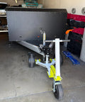 Monster Tug Off-Road Trailer Dolly Moves Boat, RV, Or Utility Trailer With Ease On Sand, Dirt, Gravel, Concrete Hard Surfaces Heavy Metal Frame Manual Mover No Motor Needed Adjustable Ball Mount For Any Tow in a garage with a trailer.