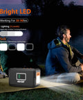 Man sitting by lake with Portable Power Station 120W 240W Peak Solar Generator With 88Wh Battery, showing LED lighting.