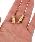 Gold-finish metal table pins and dowels set for furniture joints and desk assembly alignment held in hand.