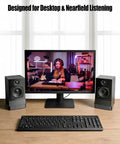 Desk Speaker Stands With 16 Degree Tilt, Wedge Riser And Anti Vibration Foam, black, next to a computer monitor on a desk.