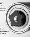 Close-up of Portable Manual Coffee Grinder With Ceramic Burr, showing adjustable settings knob with grind finer and coarser options.