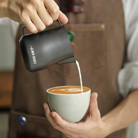 12 Oz Stainless Steel Milk Frothing Pitcher For Espresso And Latte Art Black Round Spout Milk Jug pouring milk into coffee