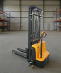 Compact Electric Pallet Stacker Forklift For Smooth Warehouse Moves with adjustable forks and control handle in a spacious warehouse.