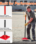 Man using 8 By 8 Inch Steel Tamper Tool With 48 Inch Handle, Heavy Duty Back Saver Hand Compactor on gravel, ergonomic handle detail.