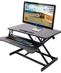 31.5 Inch Height Adjustable Standing Desk Converter Featuring Ergonomic Keyboard Tray And Monitor Riser, showcasing sleek black design and gaming setup.
