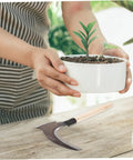 Portable Manganese Sickle for Weeding and Harvesting on wooden table next to potted plant, ergonomic and durable design