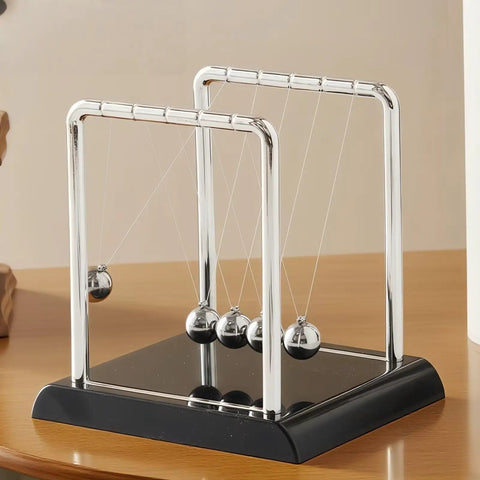 Cradle Balance Pendulum Balls Set With Black Base, Kinetic Fidget Desk Toy, metal balls on nylon hangers, on a wooden desk