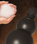 Close-up of black 900ml hydration bottle with gourd-inspired shape, made from safe PP, next to silicone granules in a hand.