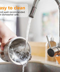 Hand holding 18/8 Stainless Steel Mortar And Pestle Set being washed under a faucet, highlighting easy cleaning of the kitchen tool.