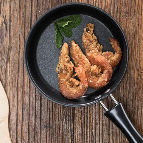 4.7 Inch Mini Nonstick Egg Pan For One Egg Frying Perfect Omelets And Pancakes On The Go Portable Camp Kitchen Pan For Gas And Induction Stoves With Ergonomic Handle Black, with fried shrimp inside on rustic table