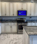 Modern kitchen with marble countertops and stainless steel appliances, featuring gold and black knurled 5-inch center bar cabinet pulls.
