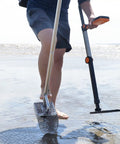 Person using Sand Scoop For Metal Detecting Stainless Steel Beach Treasure Dig Tool With Adjustable Long Handle on wet sand.