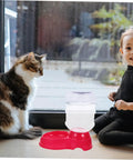 Chill Out As Your Furry Buddies Chow Down On This Pink 3.5L Automatic Pet Feeder And Water Bowl Station Featuring A Tight Leak Proof Cap And Grippy Non Slip Bottom with a cat and child.
