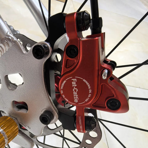 Fat-Cattie red hydraulic disc brake caliper with 160mm rotor on front wheel (close-up view)