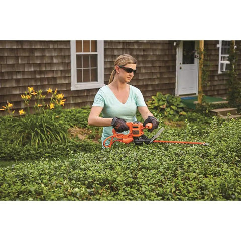 Person using 16 Inch Hedge Trimmer With Dual Action Blade And Saw Blade 3.0 Amp Motor Delivers Less Vibration Cuts Branches Up To Five Eighths Inch Ideal For Hedging Shrubs And Bushes.