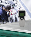 5-in-1 for stud Finder Sensor Wall Scanner LCD Display 5-in-1 on a workbench with technician in background.
