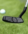 Close-up of 35 Inch Right Handed Golf Chipper With 32 Degree Loft, black head, focused on grooves, with golf ball on green.