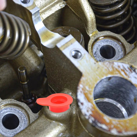 Red PVC internal thread dust plug sealing an engine hole, showing use in industrial machinery.