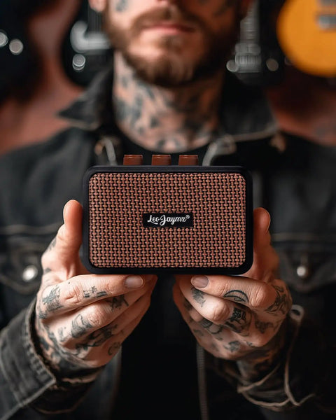 Person holding ultra portable 5W dual speaker Bluetooth guitar amplifier with rechargeable battery, clean and overdrive modes.