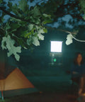 Siege AA 200-Lumen Lantern With White And Red LEDs for camping and emergencies hanging from tree branch near tent at night