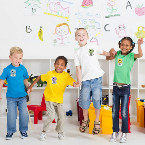 Children wearing Smiley Name Tags Pack 120 Pcs Boho Pastel Smile Face Nameplates, posing in colorful classroom setting.