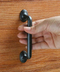 Hand holding Rustic Black Silver Cabinet Handles Set Of 10 Drawer Pulls Zinc Alloy One Piece Die Cast Construction on wooden drawer