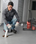Heavy Duty 75 Ft Electric Drain Cleaner Auto Feed Sewer Snake Auger in use with operator feeding cable into a pipe.
