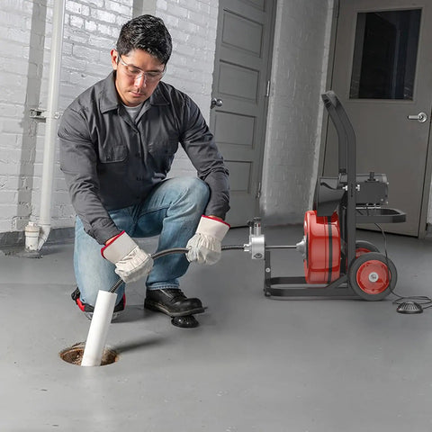 Man using Heavy Duty Electric Sewer Auger Tough As Nails Walk Along Drain Cleaner to clear a clogged pipe.