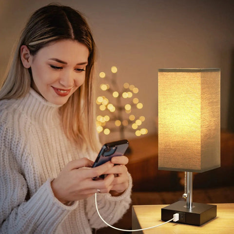 Woman using phone next to small nightstand lamp with USB, black shade for end tables, set of 2 bedside lamps with dual USB ports