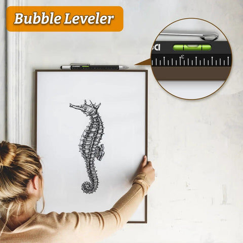 Woman hanging seahorse art using a level tool with focus on bubble leveler.