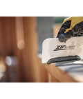 Person applying Fluid Applied STPE Liquid Flashing Sealant In 29 Oz Cartridge with a scraper on a wooden surface.