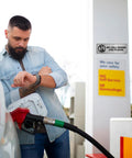 Person at fuel pump with 'No Cell Phone Use Please' sign visible on wall