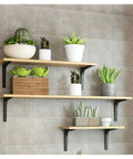 Heavy Duty L Shaped Corner Wall Mount Shelf Brackets With Thickened Steel Build For Floating Industrial Storage That Handle Load Like No Sweat And Bring Major Clean Vibes To Your Space In Black with wooden shelves and potted plants.