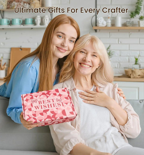 Two women smiling, one holding a pink gift box labeled 'Best Wishes' in a cozy home setting.