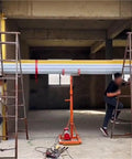 Industrial hoist system lifting a metal beam in a warehouse, showcasing Built Different Heavy Duty Overhead Winch Crane.