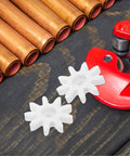 Two white plastic gears from a 4 Piece 9 Tooth Plastic Gear Set For Gumball Machines And Coin Operated Dispensers on a wooden surface.