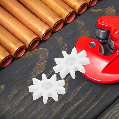 Two white plastic gears from a 4 Piece 9 Tooth Plastic Gear Set For Gumball Machines And Coin Operated Dispensers on a wooden surface.