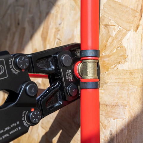 Close-up of Pex Crimping Tool Dual Size One Half Inch And Three Quarter Inch Heavy Duty for copper ring crimping on red pipe.
