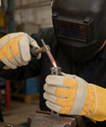 Worker using Tough As Nails Cowhide Split Finger Welding Gloves For Men, Heat Resistant Yellow Work Gloves for welding tasks.