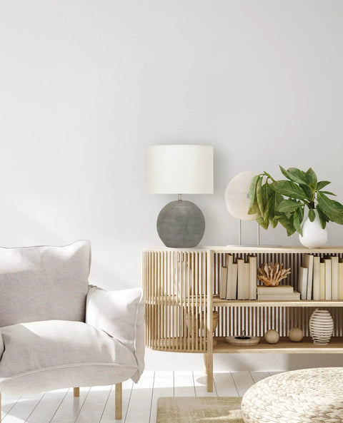 Round Terracotta Table Lamp With Canvas Shade In Distressed Grey Finish on bookshelf with plants and books, cozy living room setting