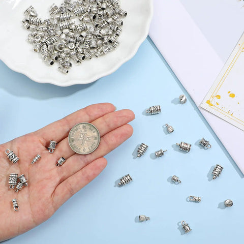 Hand holding antique silver cord end cap from 100 Pcs Cord End Caps Jewelry Making Kit With Five Styles In Antique Silver Alloy Tips Plus Lobster Clasps And Jump Rings For DIY Bracelets Necklaces And Anklets Create Custom Bling With Ease.