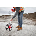 Rugged 12 Inch Digital Measuring Wheel With IP54 Backlit Display in use on gravel site for accurate distance tracking.