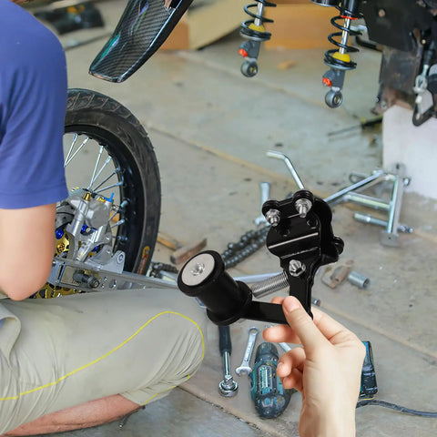 Top Notch Motorcycle Chain Tensioner Kit With Roller Guide For Off-Road Bikes Durable Iron Make Your Ride Safe And Smooth Corrosion Resistant Gear To Keep Things Tight. black iron tensioner kit with roller guide, shown in hand beside a dirt bike wheel