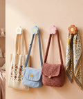 Four Pack Hand Carved Wood Daisy Wall Hooks Decorative Multi Color Coat And Robe Hanger Rack For Bathroom Kitchen Nursery 3 bags and a scarf hanging on flower-shaped hooks.