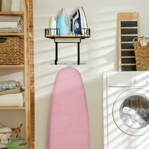 Laundry room with wall mounted ironing board hanger and iron holder with large black wooden base basket, pink board visible.